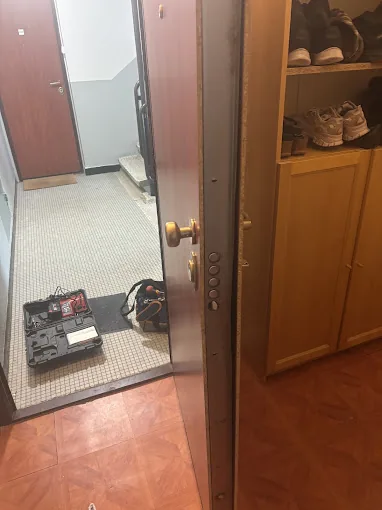 Porte d'entrée ouverte avec la caisse à outils du serrurier posée au sol