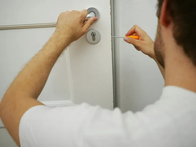 Serrurier ajustant le cylindre d'une serrure de porte avec un tournevis